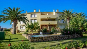 A multi-story hotel with a landscaped garden, including palm trees and a fountain.