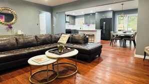 Un salon moderne avec un canapé en cuir, une table basse et un coin repas comprenant une table et des chaises.