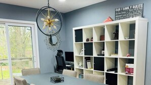 Un coin repas avec une table et des chaises, une bibliothèque et un luminaire décoratif au plafond.