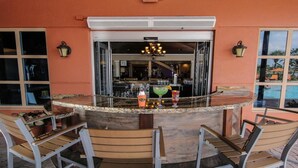 Zona de bar amb un taulell de granat corbat, tamborets i un llumser.