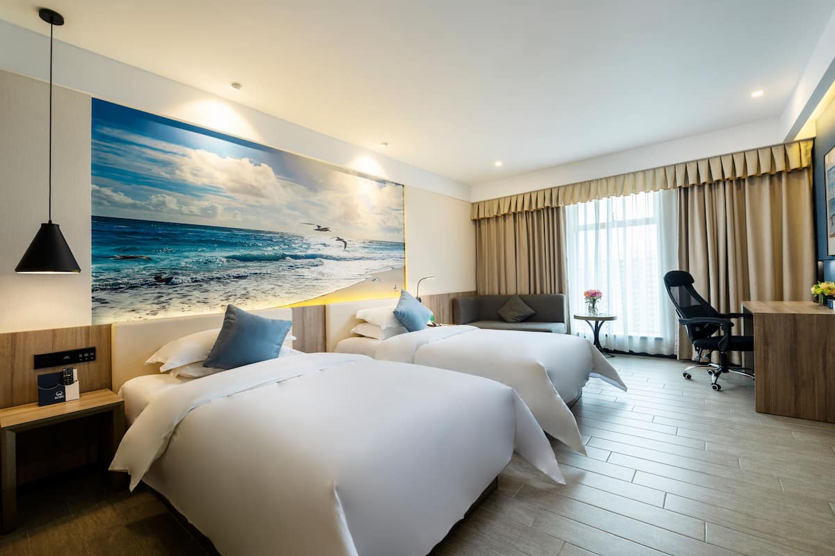 Habitación de hotel con dos camas, un escritorio, una silla y un gran mural marino.