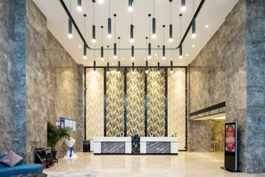 A modern lobby with a reception desk, seating area, and a large patterned wall. - Dongguan Haili Hotel (Dongguan)