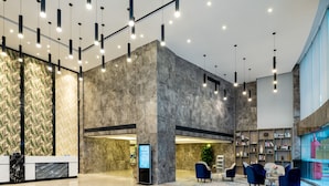 Un vestíbulo moderno con un mostrador de recepción, zona de estar y una gran pantalla digital.