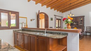 Una cocina con armarios de madera, encimeras de granito, un lavamanos integrado y techo de madera.