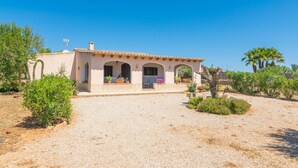 Una villa de estilo mediterráneo con camino de grava, entrada abovedada y plantas en macetas.