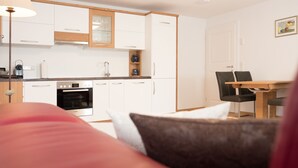 Eine moderne Küche mit weißen Schränken, einem Bosch-Ofen und einem Essbereich mit einem Holztisch und schwarzen Stühlen.