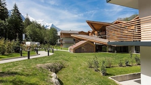 Un edificio moderno con techo inclinado, terraza de madera y vista a la montaña.