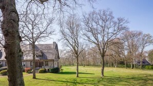A house with a sloped roof and a chimney, surrounded by a grassy yard with trees.
