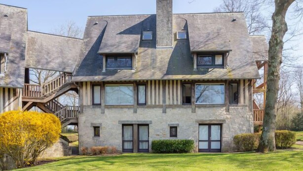 A modern two-story house with a stone facade, multiple windows, and a prominent chimney.