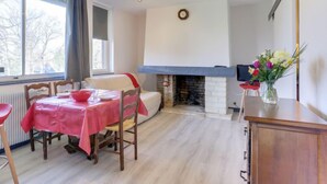 A cozy room with a dining table set for two, a fireplace, and a window with curtains.