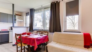 A dining area with a table set for four, a sofa, and a kitchen in the background.