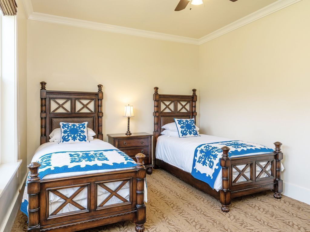 A bedroom with two wooden beds, each with a cross-patterned headboard, and a nightstand between them.