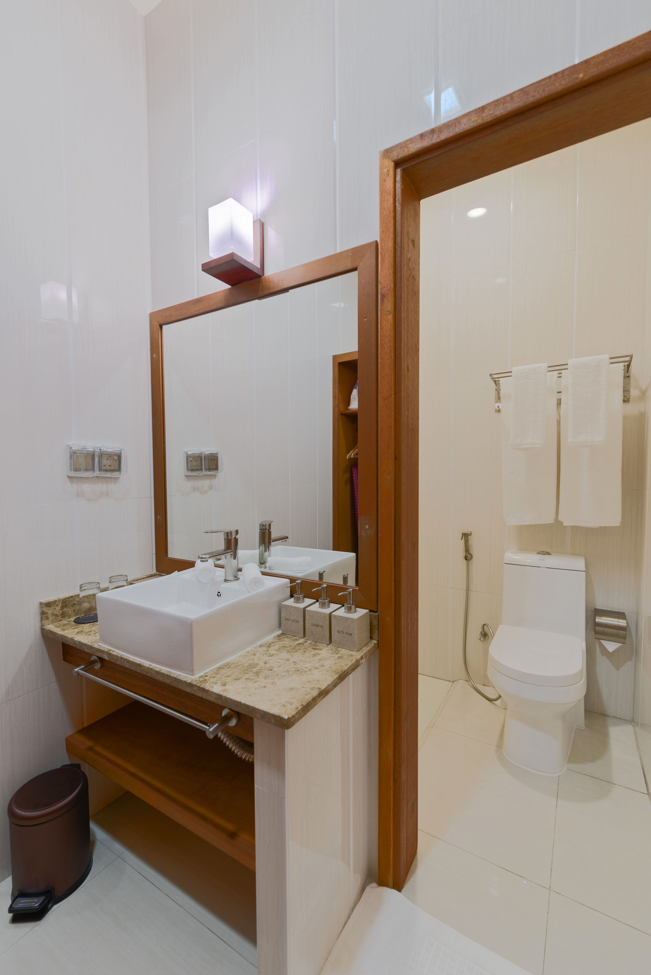 A modern bathroom with a large mirror, a sink, a toilet, and a shower.