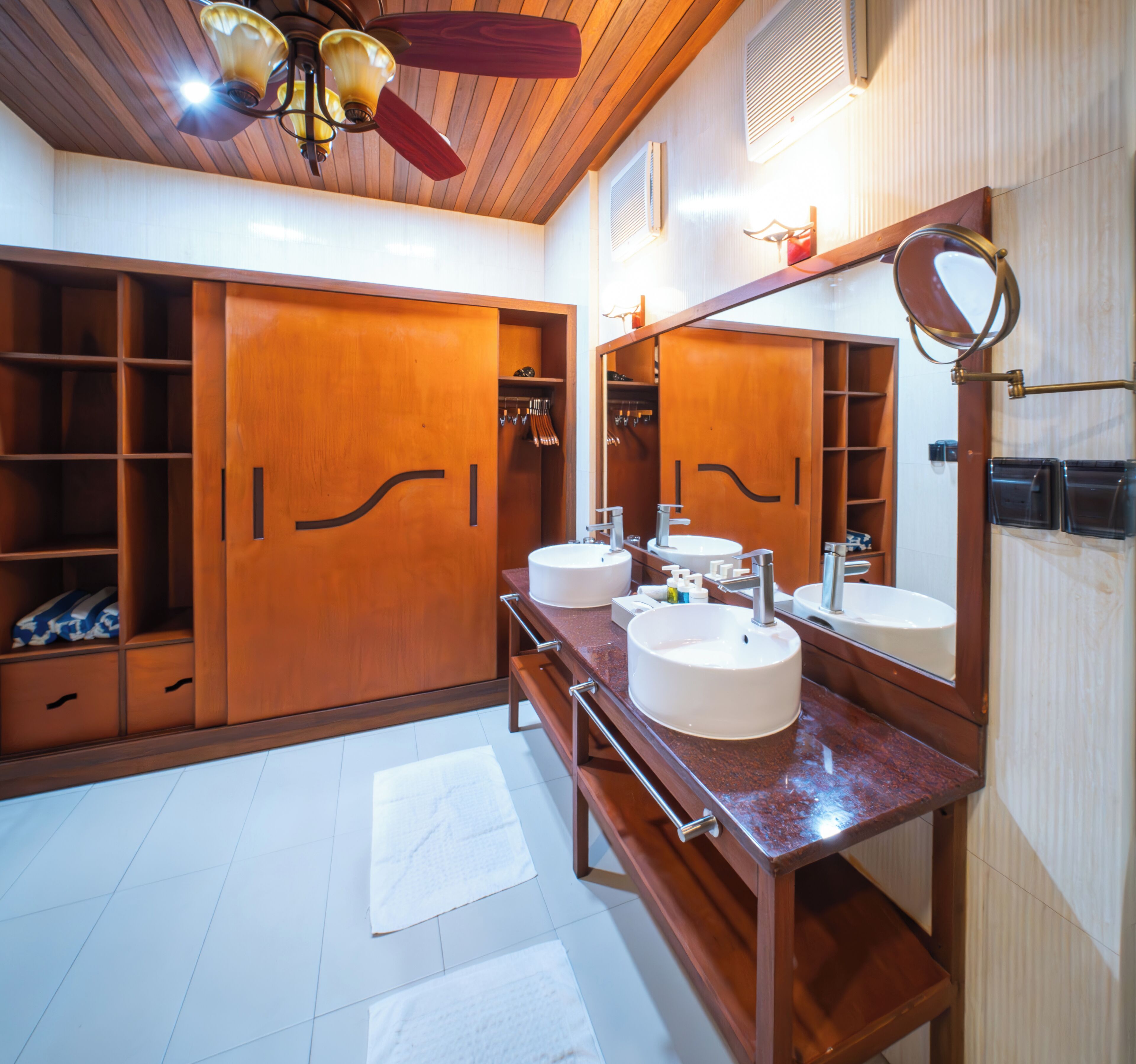 A bathroom with wooden cabinets, a large mirror, and two sinks.