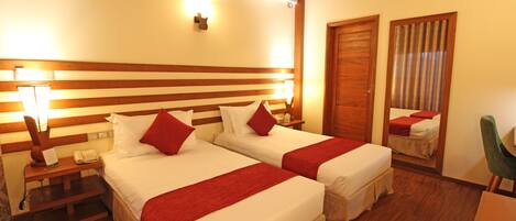 A hotel room with two beds, wooden headboard, bedside lamps, a telephone, and a mirror.