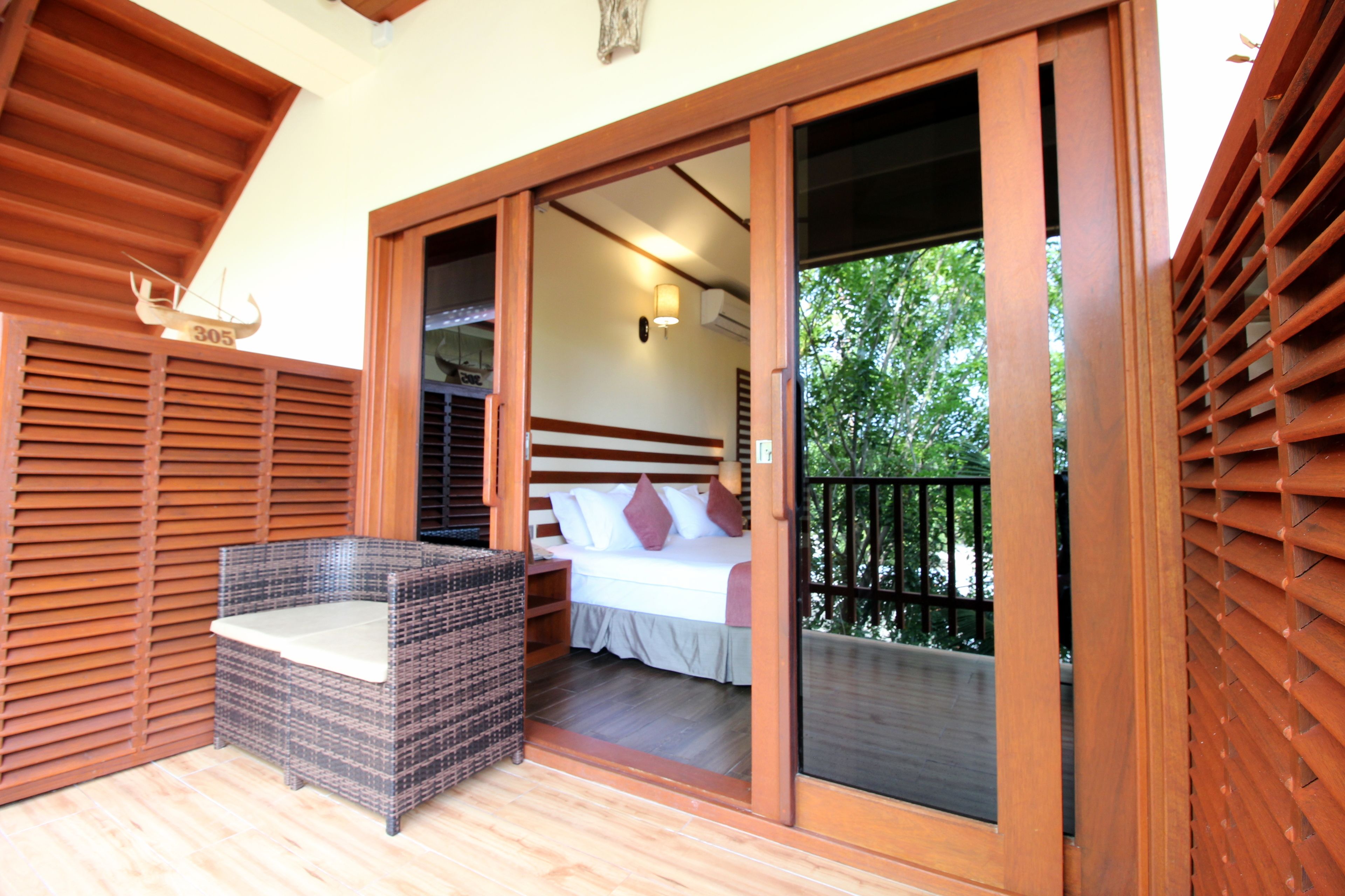 A bedroom with a bed, a nightstand, and a wicker chair.