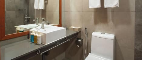 A modern bathroom with a sink, mirror, towel rack, and toilet.