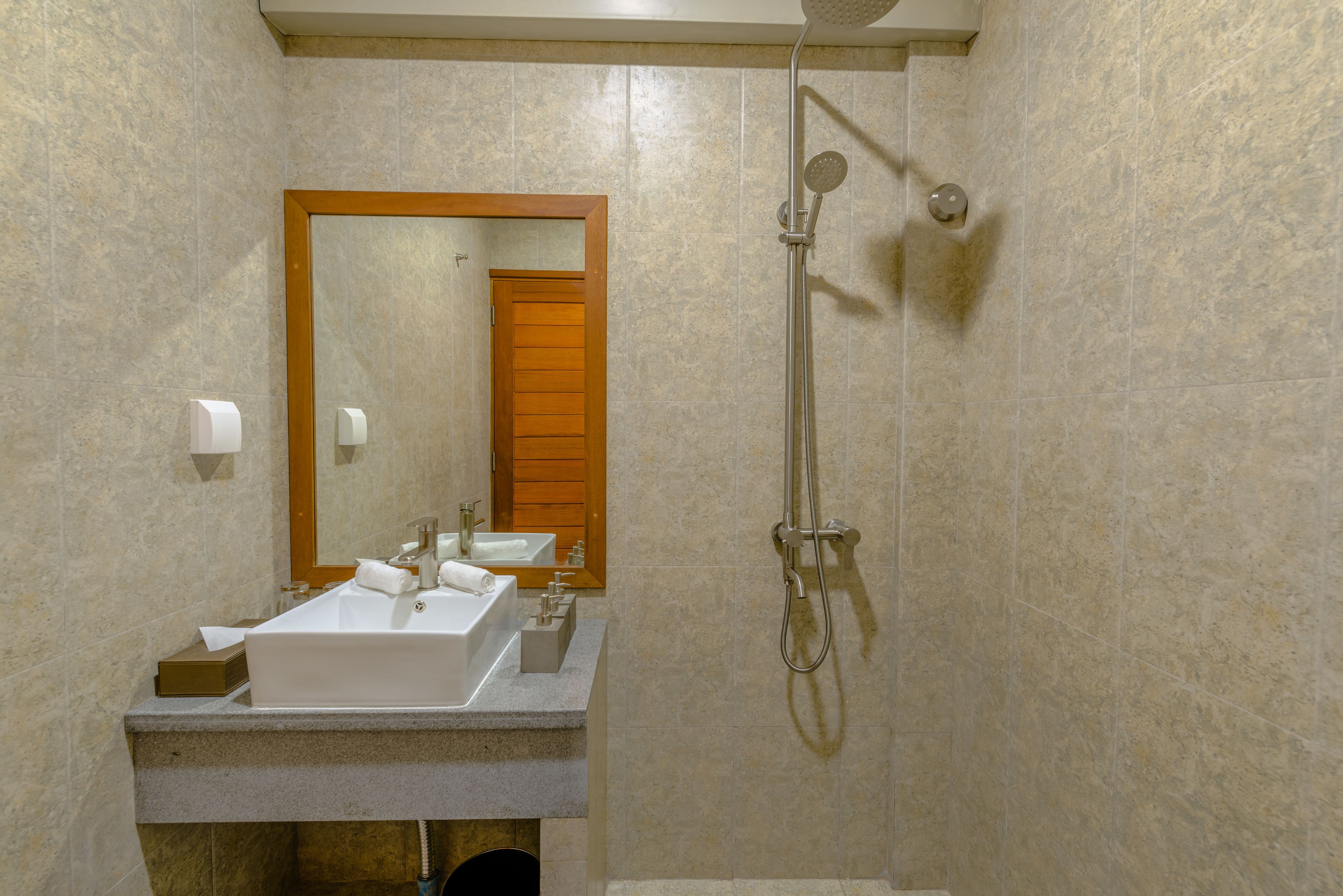 A bathroom with a large mirror, two sinks, a shower, and a towel rack.