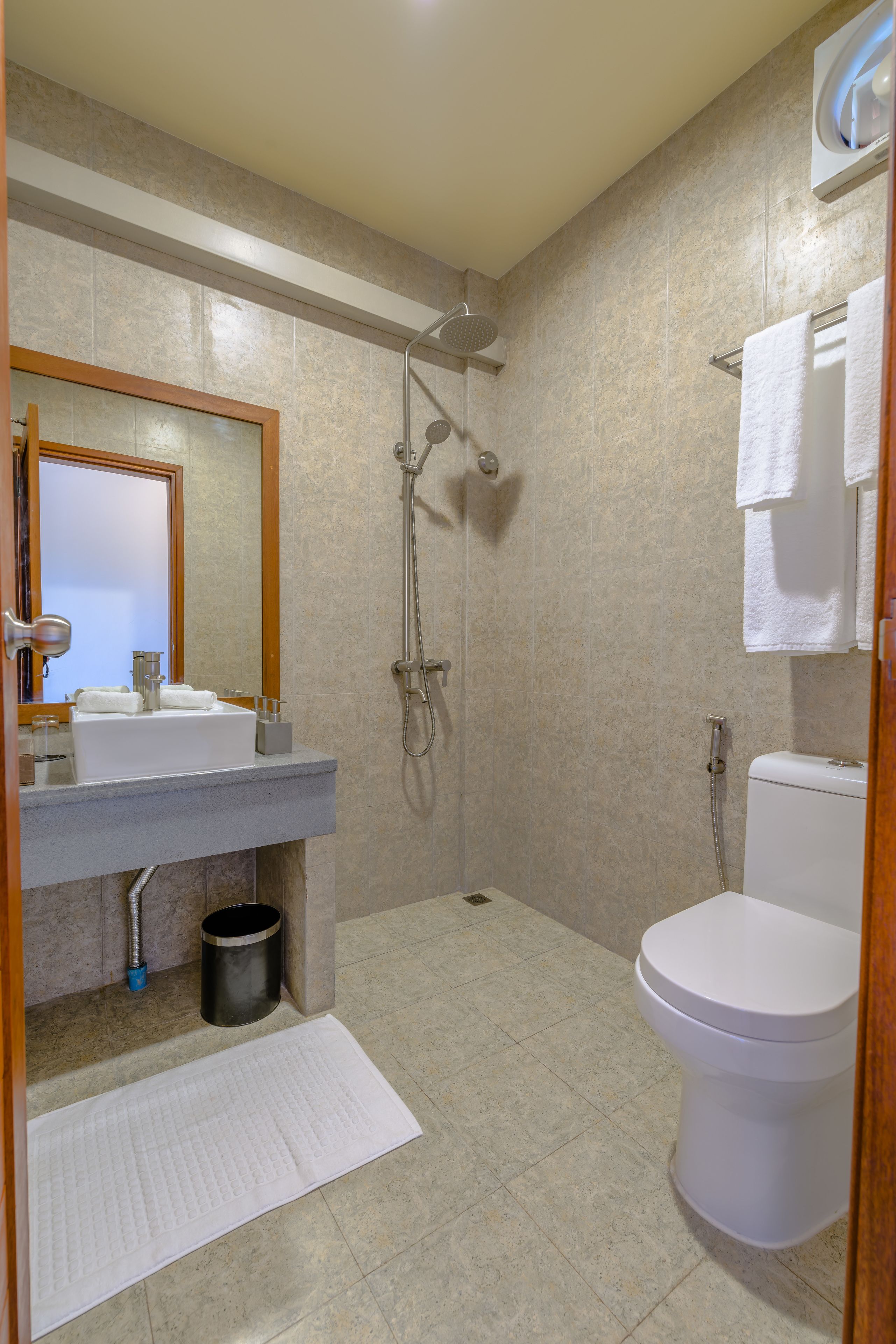 Un baño con ducha, inodoro, lavabo y espejo.