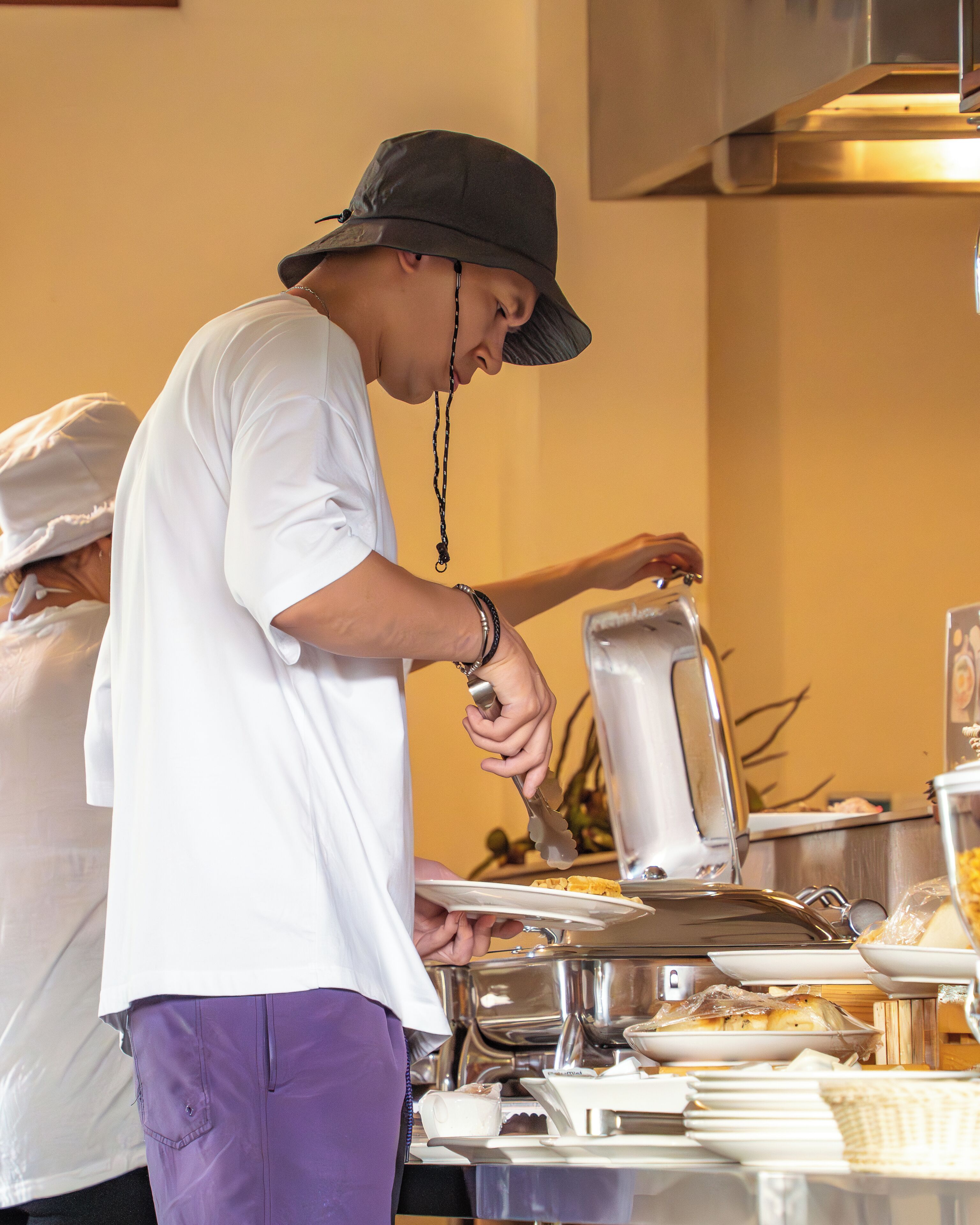 Montaje de bufé con diversas opciones de comida y una persona sirviéndose.