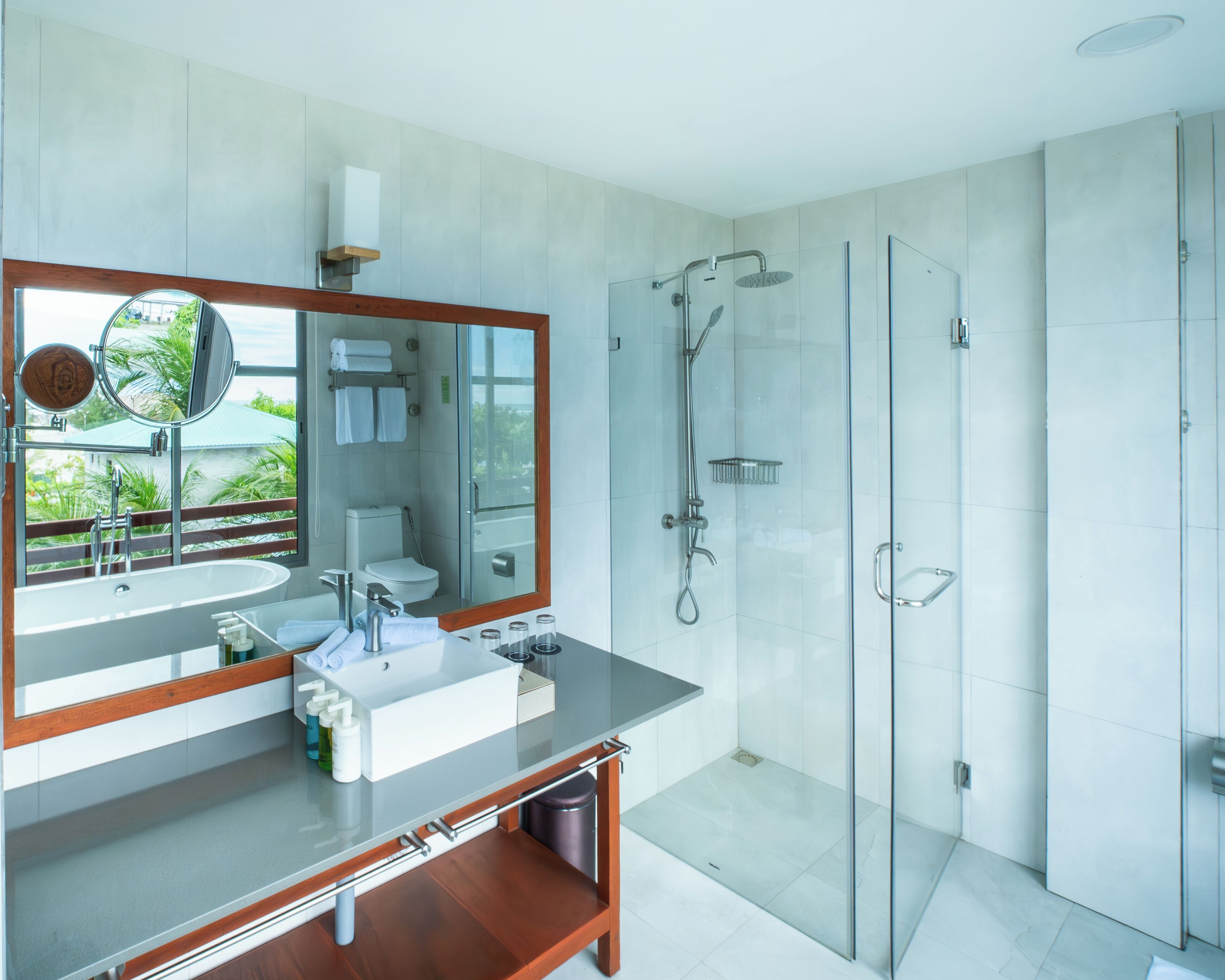 Un baño moderno con un espejo grande, un lavamanos y una ducha.