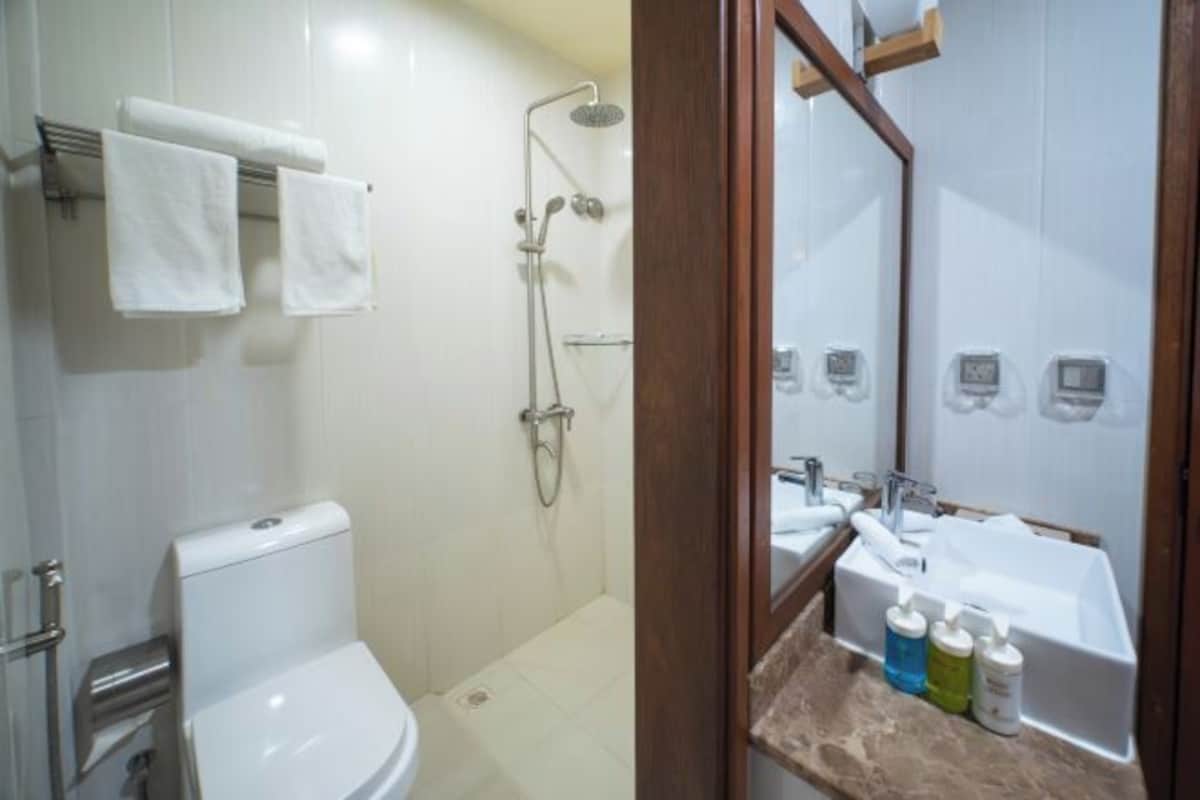 Un baño con inodoro, ducha y lavamanos con artículos de aseo.
