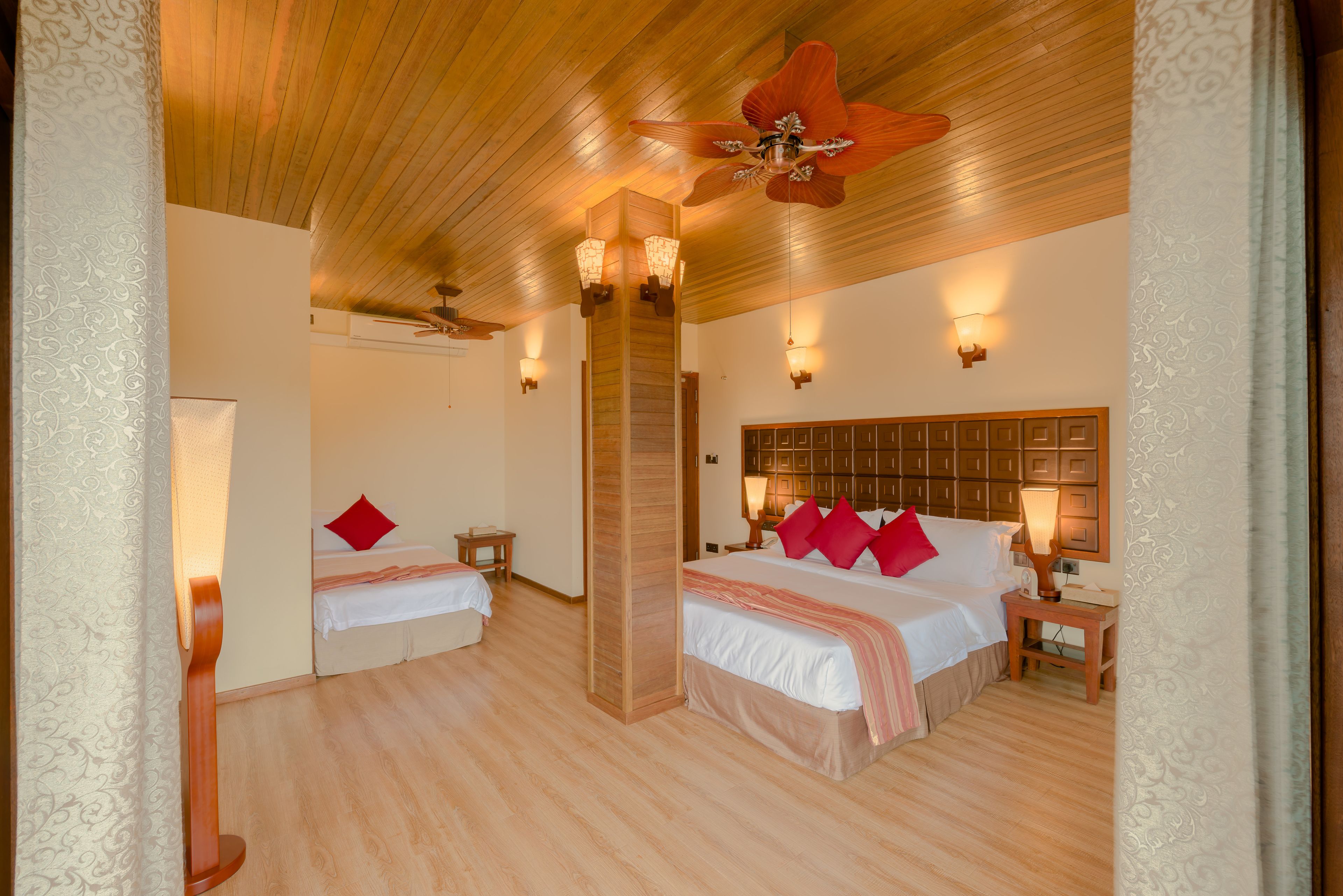Habitación de hotel con dos camas, techo de madera e iluminación en la pared.