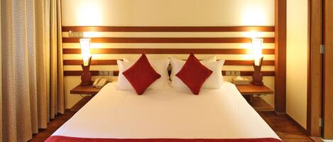 Une chambre d’hôtel avec un grand lit, deux lampes de chevet, un téléphone et une tête de lit en bois.