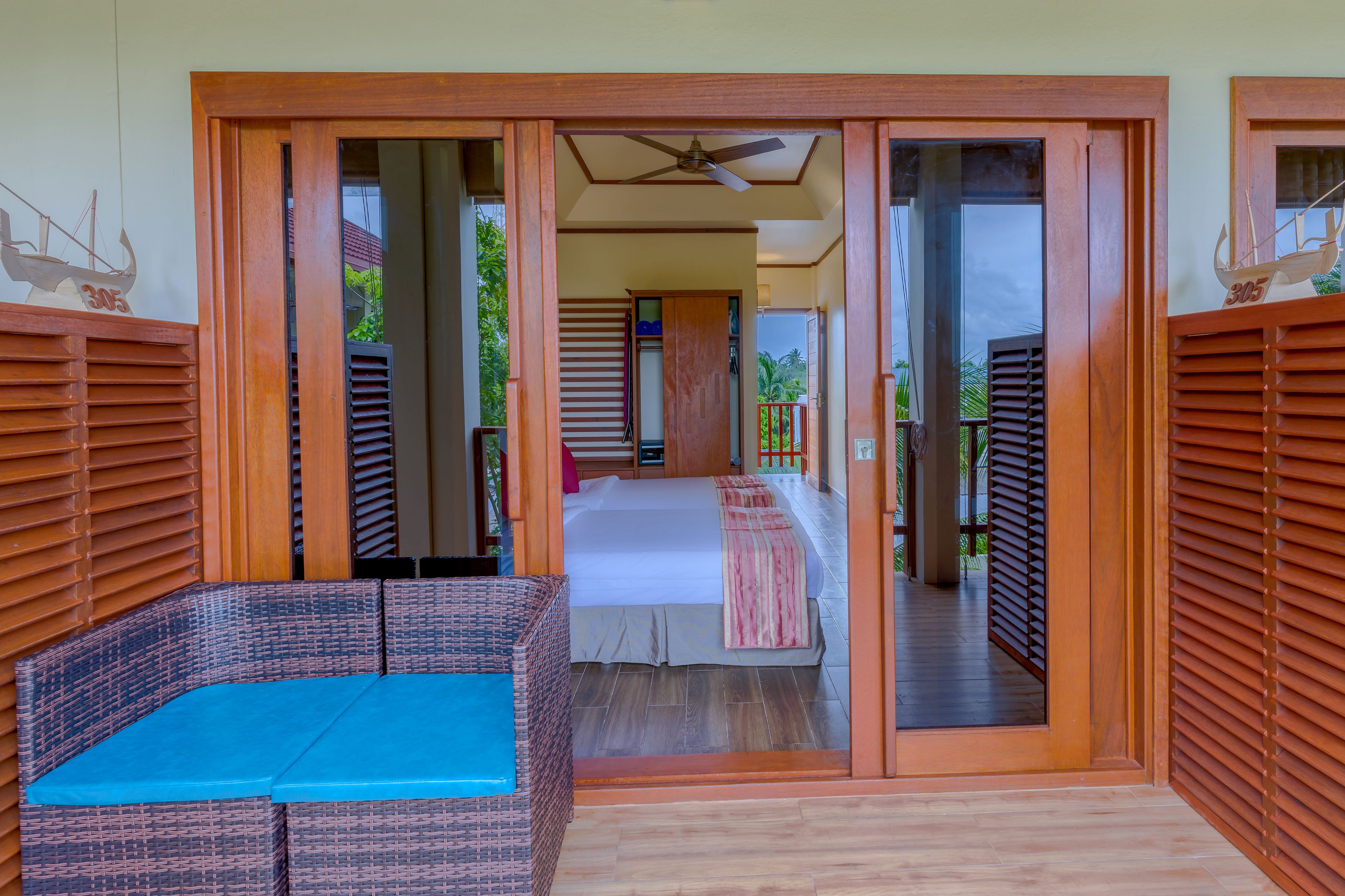 A room with a bed, a blue sofa, and a wooden door leading to a balcony.