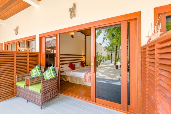 A room with a bed, a wicker sofa with green cushions, and a wooden ceiling. - Araamu Hotels Maldives (Dhiffushi)