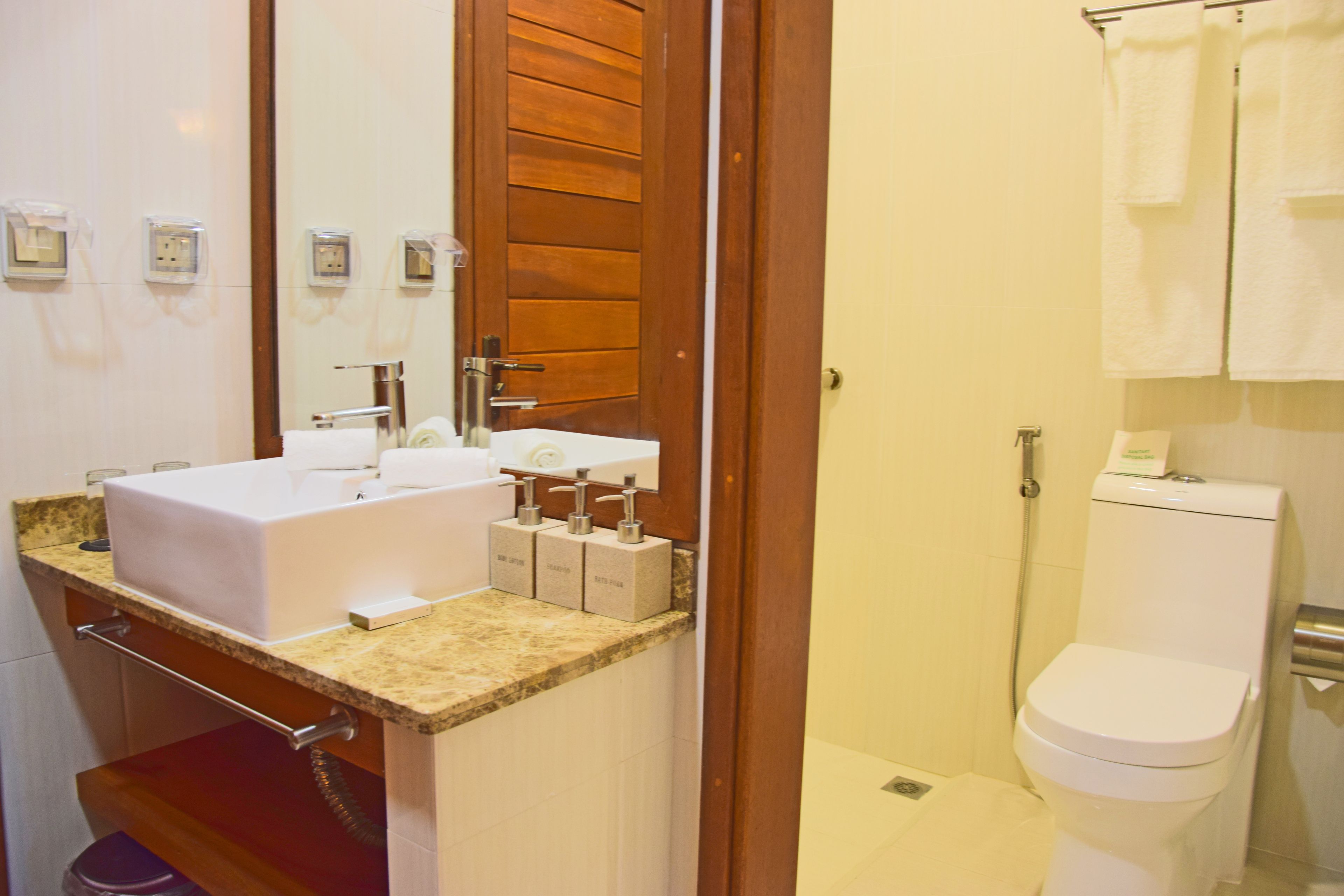 Un baño con lavamanos, espejo e inodoro.