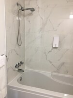 Bañera con ducha, secador de pelo, toallas, papel higiénico