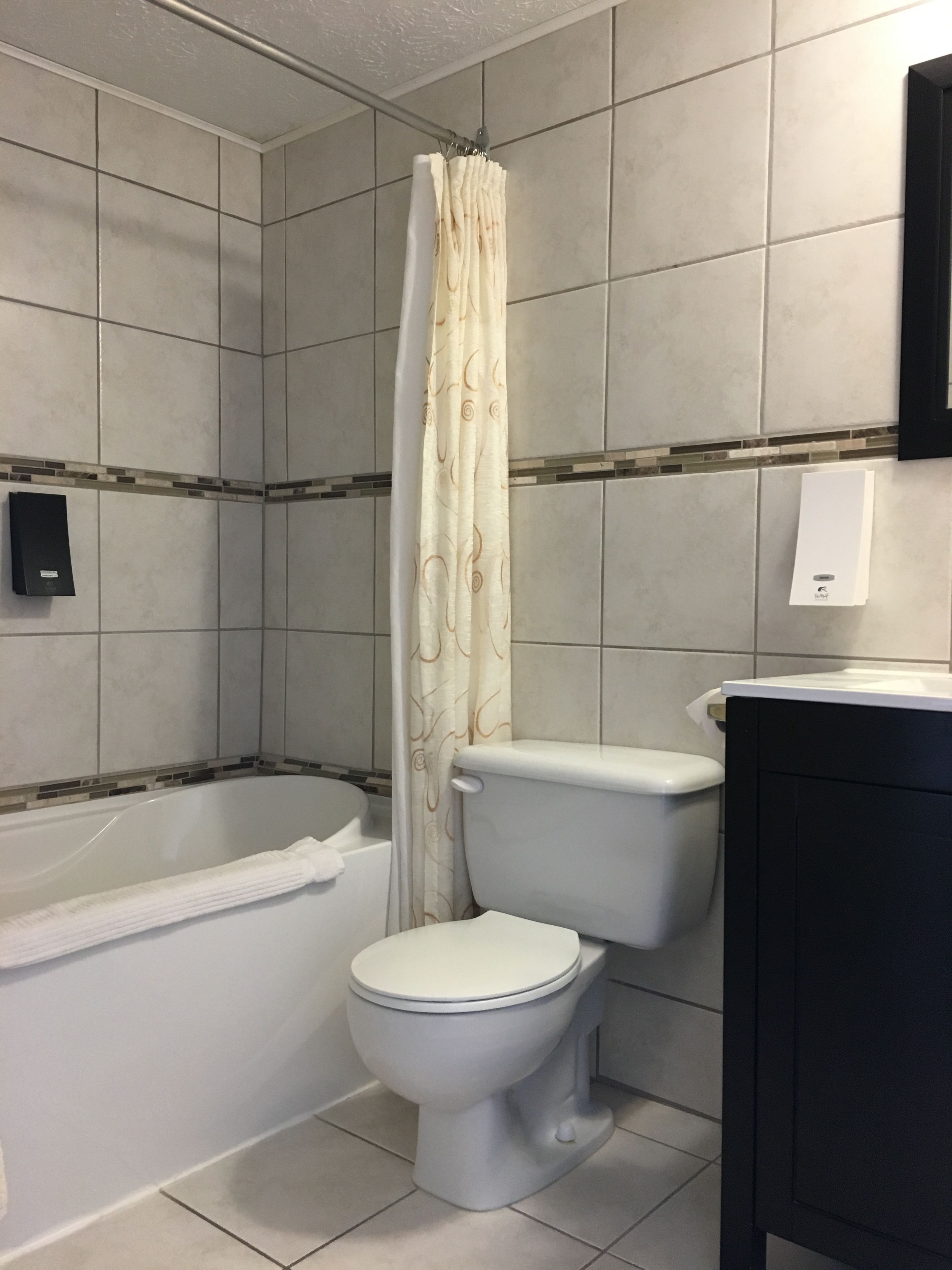 Een badkamer met een bad, toilet en douchegordijn.
