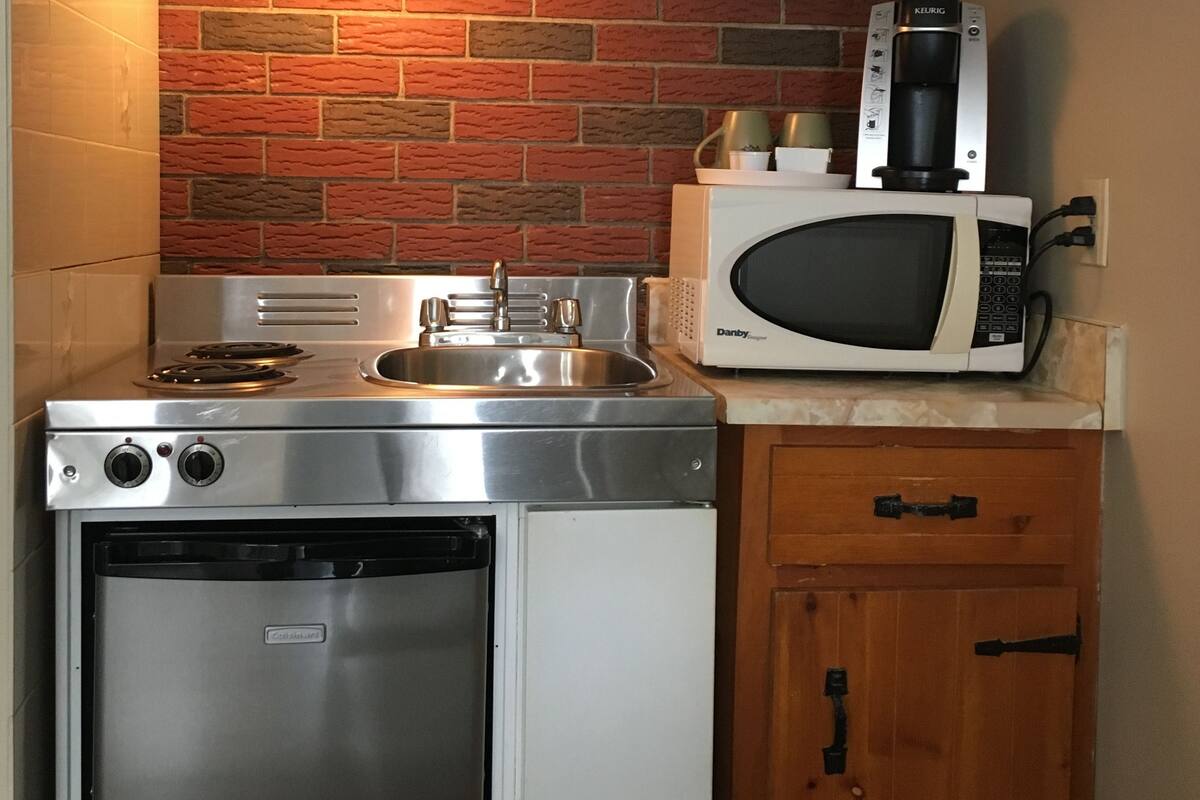 A compact kitchen with a stainless steel stove, a microwave, and a dishwasher.