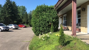 Un bâtiment doté d’un porche abrité et d’un parking où sont stationnées plusieurs voitures.