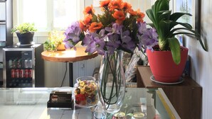 Un plan de travail de cuisine orné d’un vase de fleurs, un réfrigérateur, un calendrier et une croix accrochée au mur.
