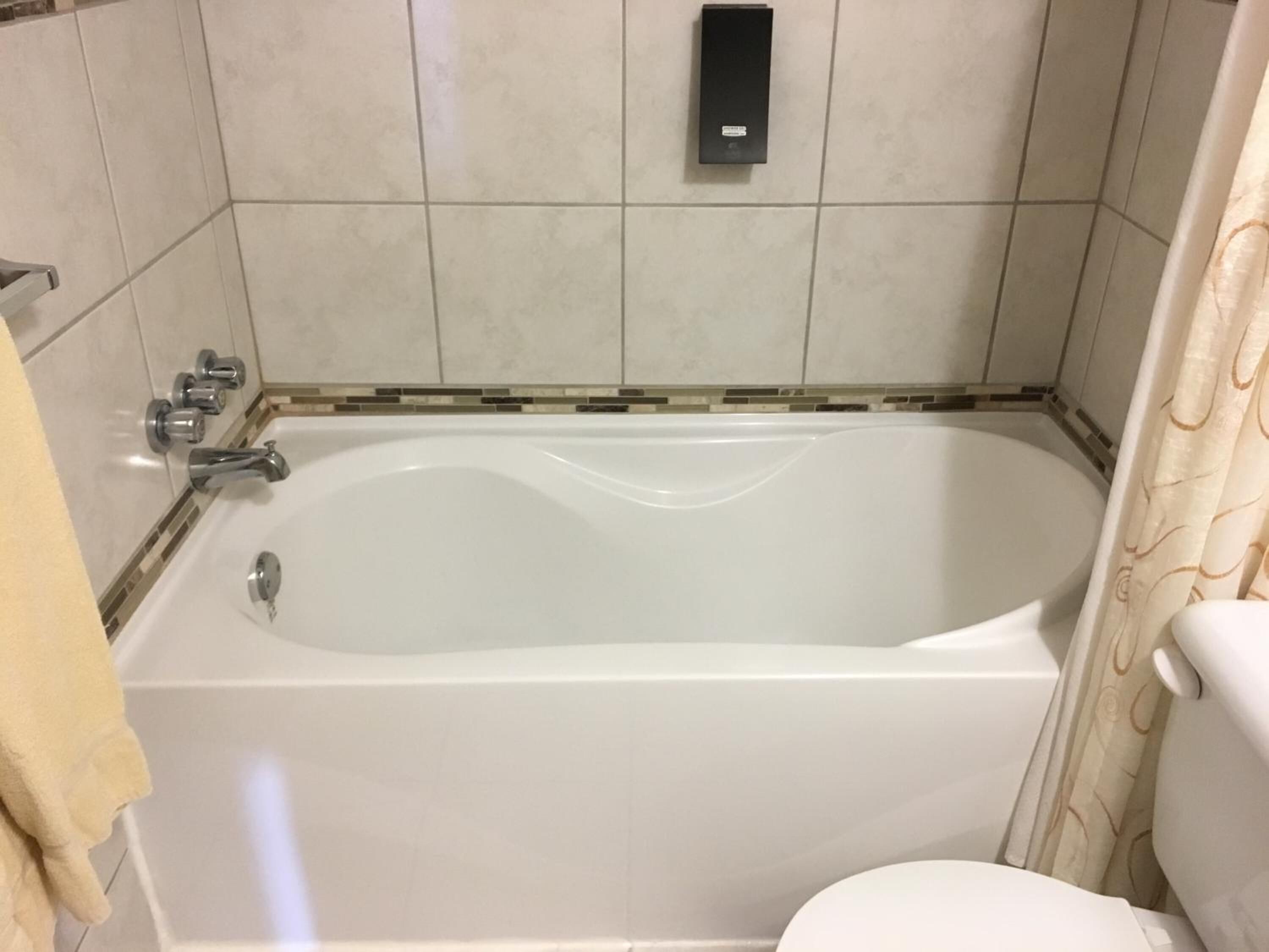 A bathroom with a bathtub, a toilet, and a towel rack.