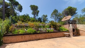 Un jardín con un muro de ladrillo, una pequeña construcción de ladrillo y una mesa.
