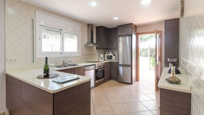 Una cocina moderna con una isla central, electrodomésticos de acero inoxidable y vistas al exterior.