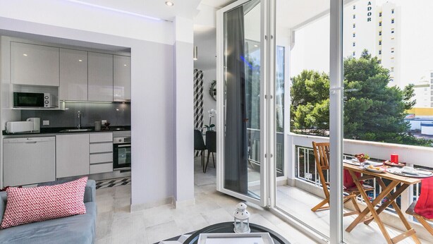 A modern apartment with a kitchen, dining area, and a balcony with a city view. - HAppy House (Cascais)