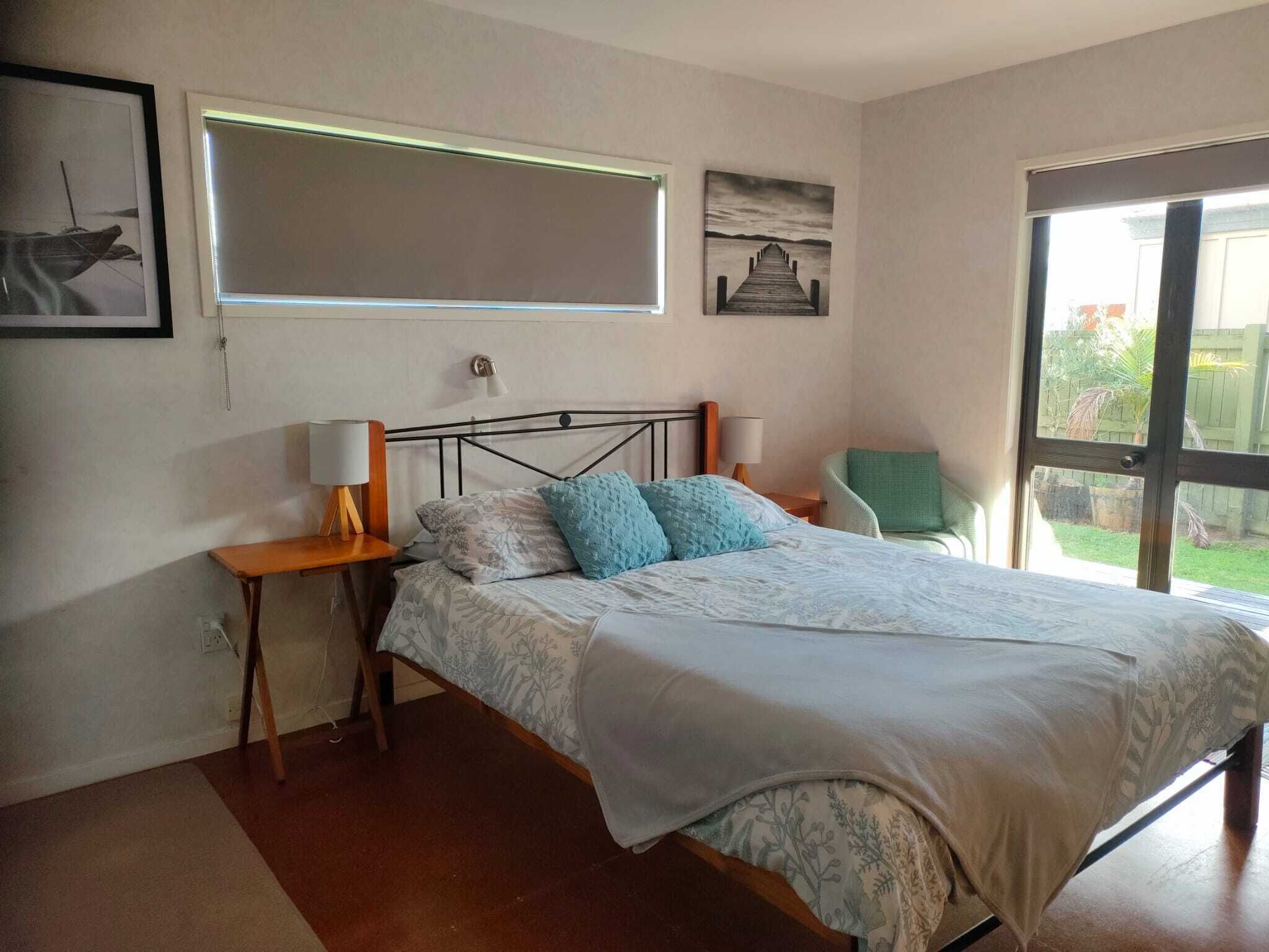 A bedroom with a bed, bedside tables, a chair, and artwork on the walls.