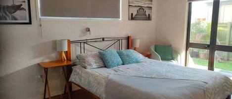 A bedroom with a bed, bedside tables, a chair, and artwork on the walls.