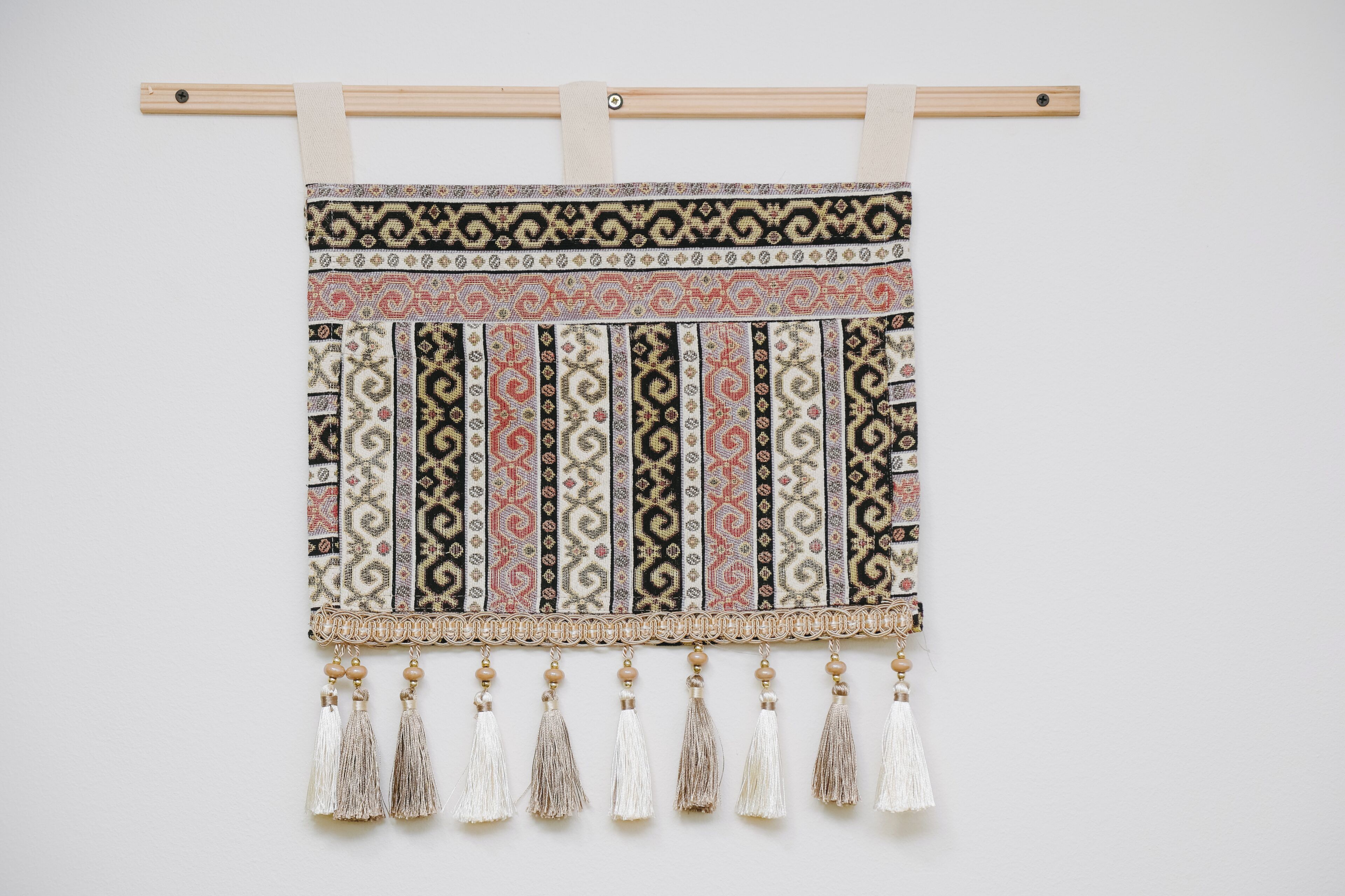Une décoration murale composée d’un tissu à motifs et de quelques glands.