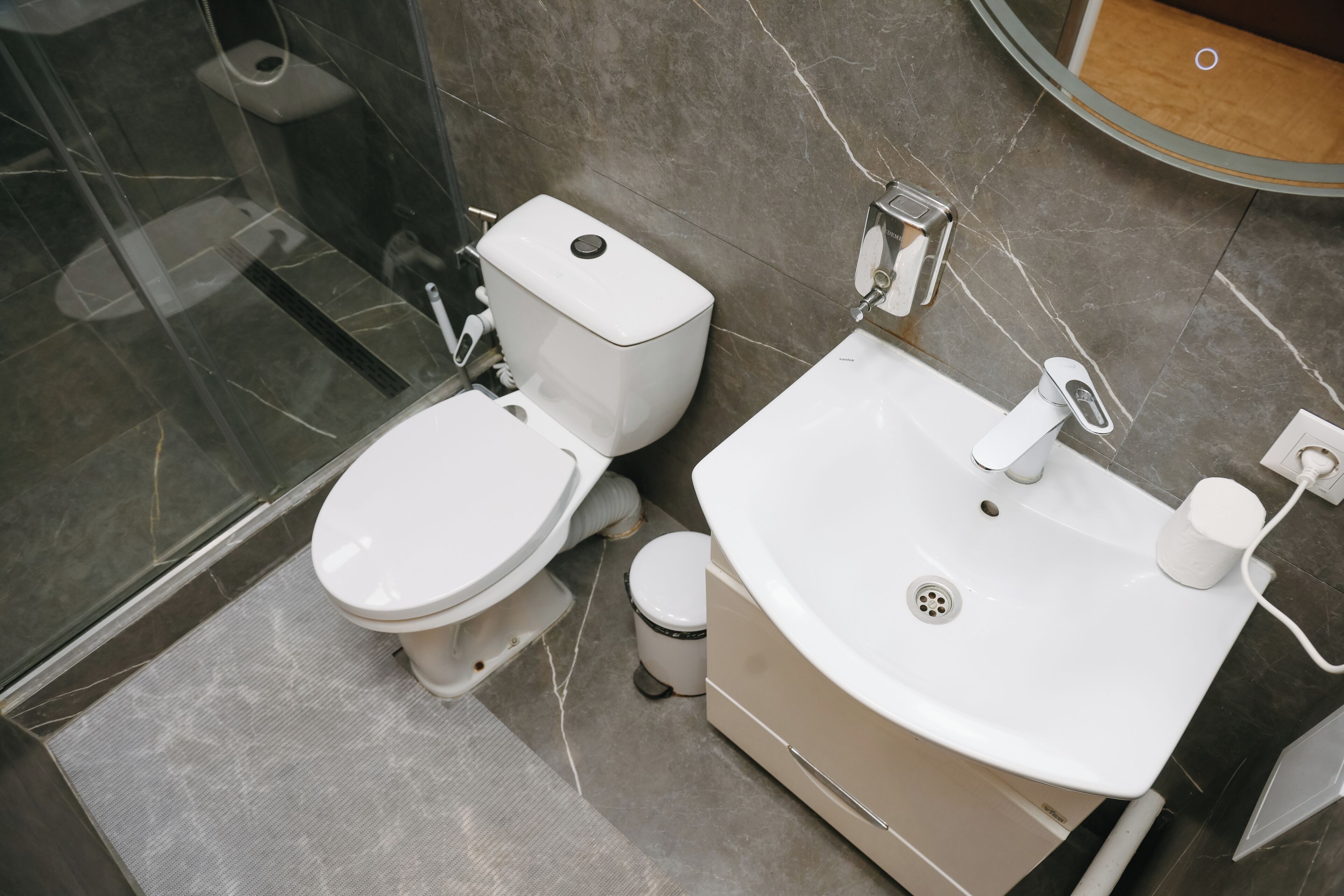 Un baño moderno con inodoro, lavamanos y ducha.