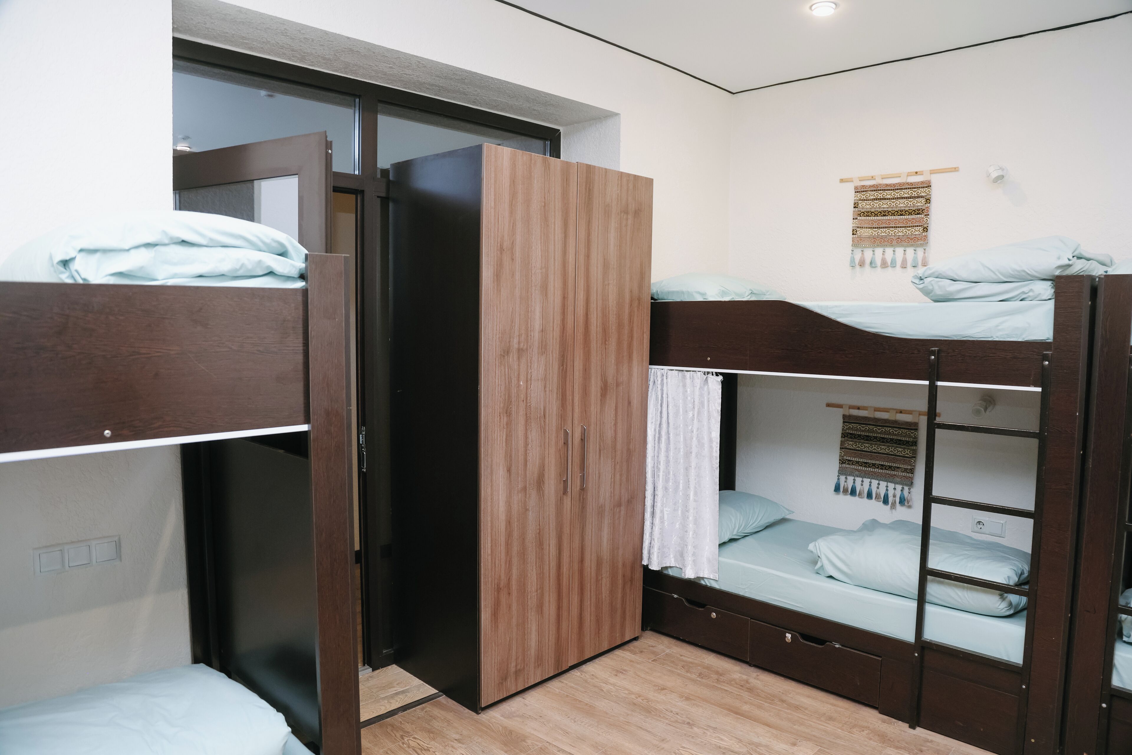 Ein Zimmer mit Etagenbetten, einem Kleiderschrank, einem kleinen Fenster und einer Wanddekoration.