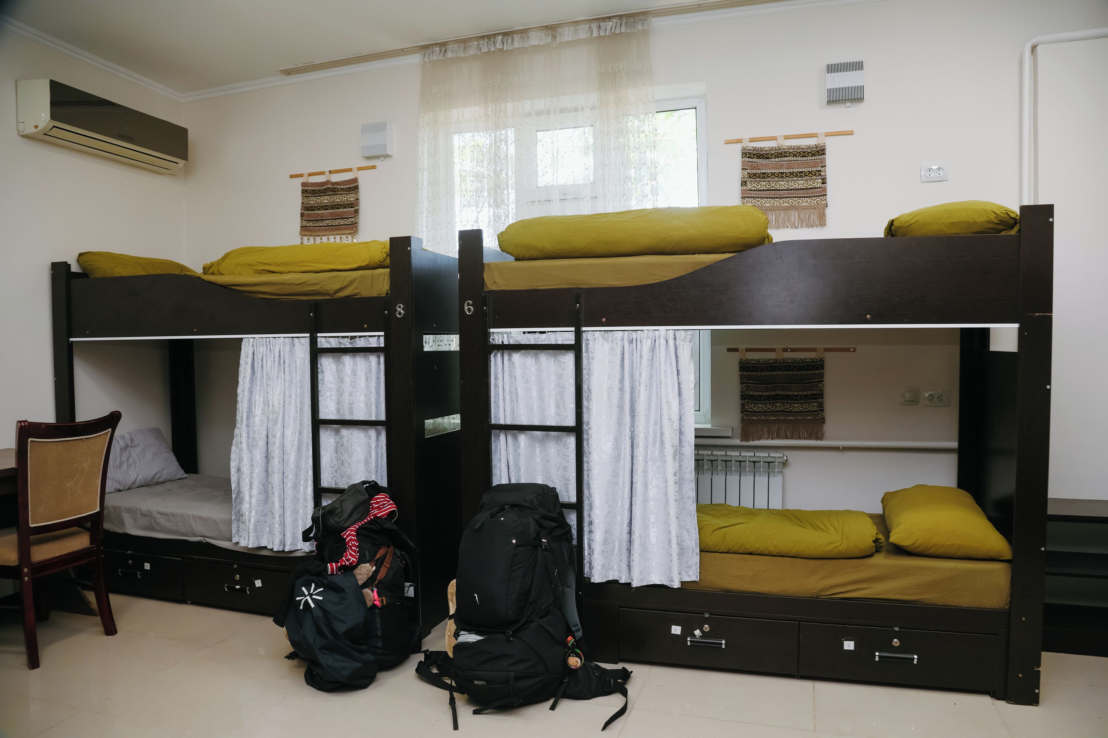 Une chambre de dortoir avec des lits superposés, une chaise et deux sacs à dos.