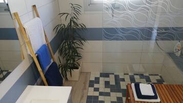 Une salle de bain avec une baignoire, un banc en bois, une plante en pot et un carrelage à carreaux.