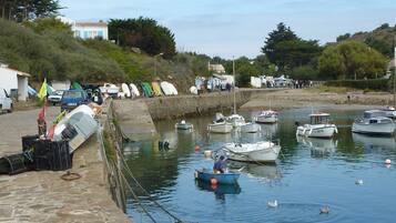 A harbor with boats docked, a stone wall, and a few people walking by.