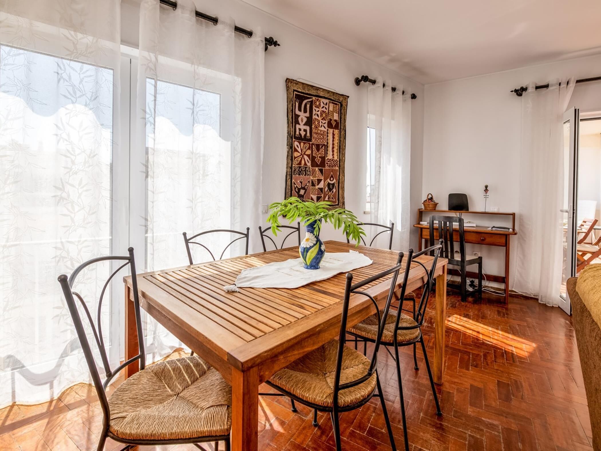 Un comedor con una mesa de madera, sillas tejidas y una planta en maceta.