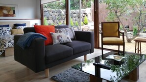 Een moderne woonkamer met een donkere bank, een gele fauteuil en een glazen salontafel.